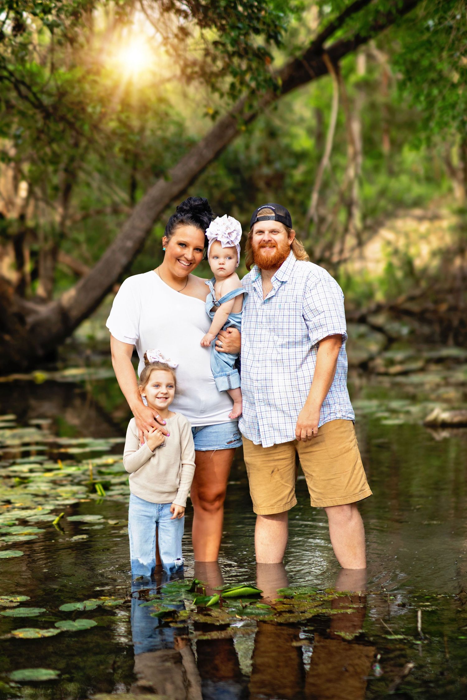 Natural outdoor family photo session in a creek with water and greenery in the background.