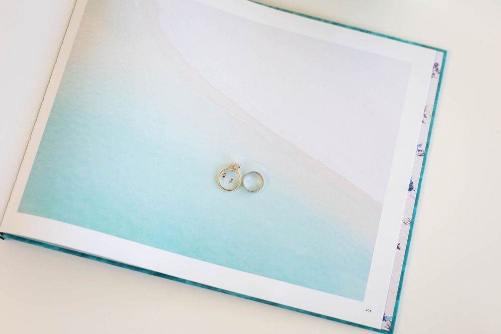 Two silver wedding rings displayed on a light turquoise page of an album or book.