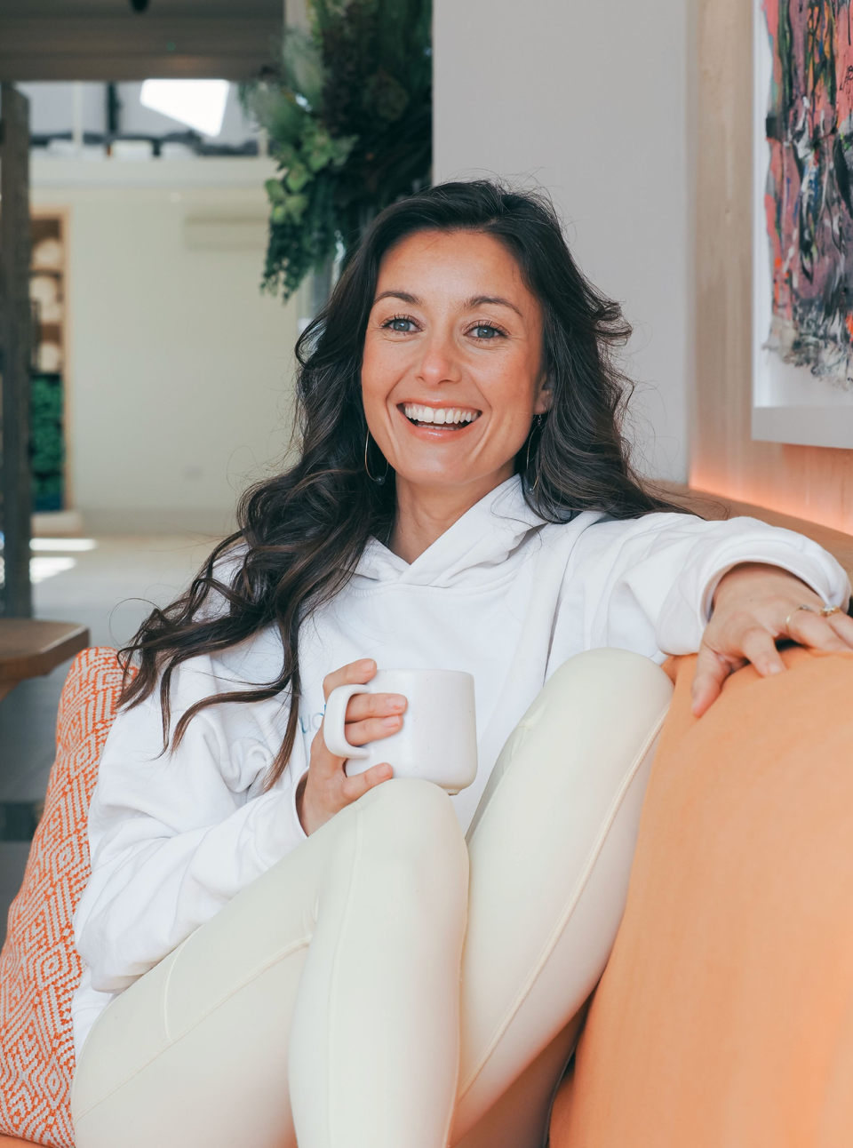 Casual business outfit featuring a beige cardigan, white tank top and black pencil skirt in a minimal white interior setting.