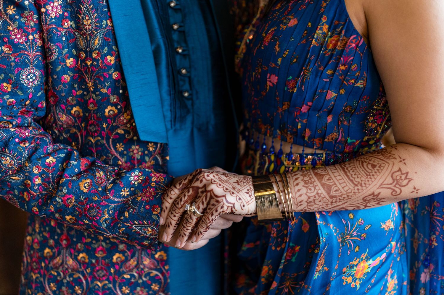 Close-up details of intricate blue and red floral patterns on traditional Indian wedding attire.