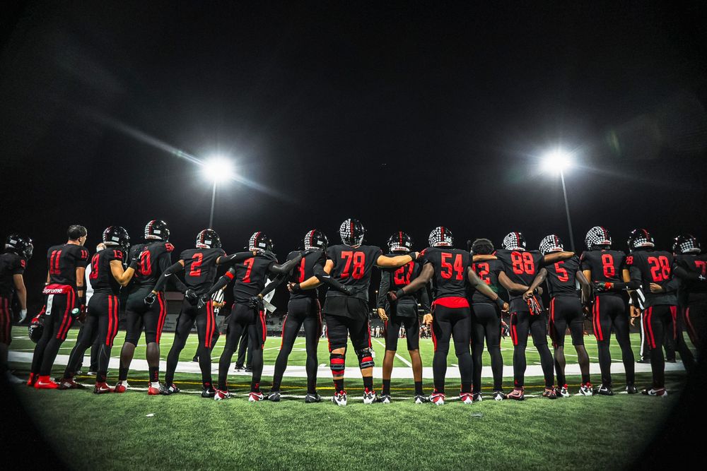 Football players standing together looking onto the field