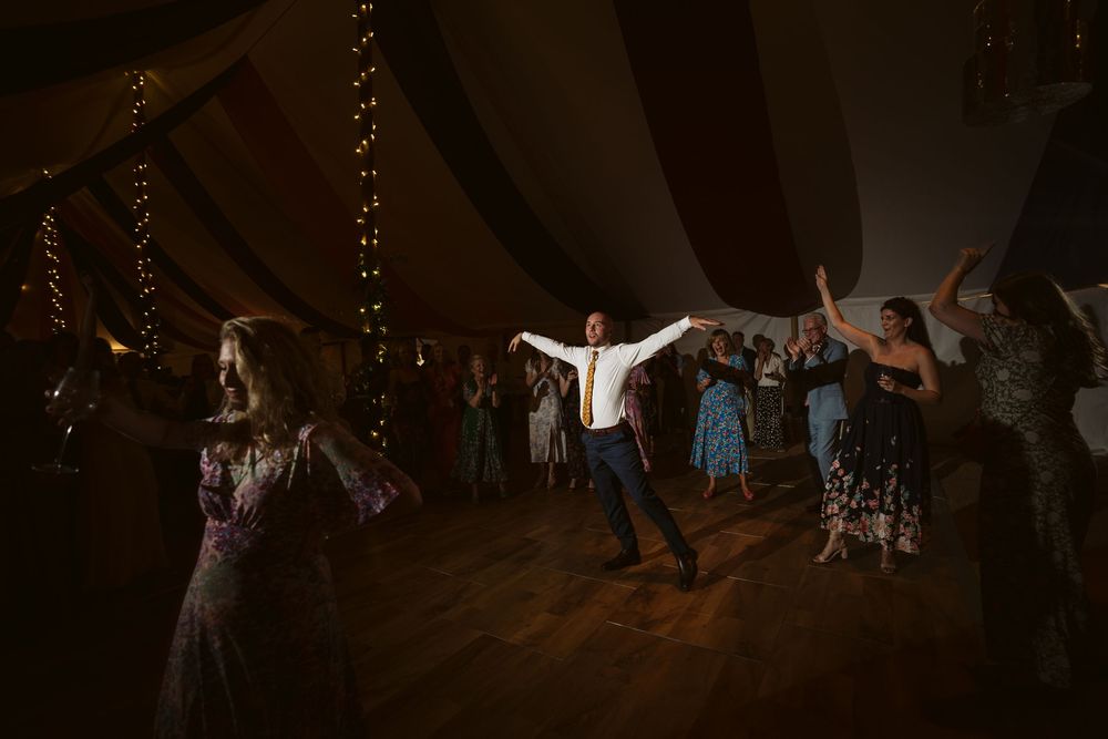 Wedding guests with arms raised celebrating on the dance floor at a Surrey wedding party
