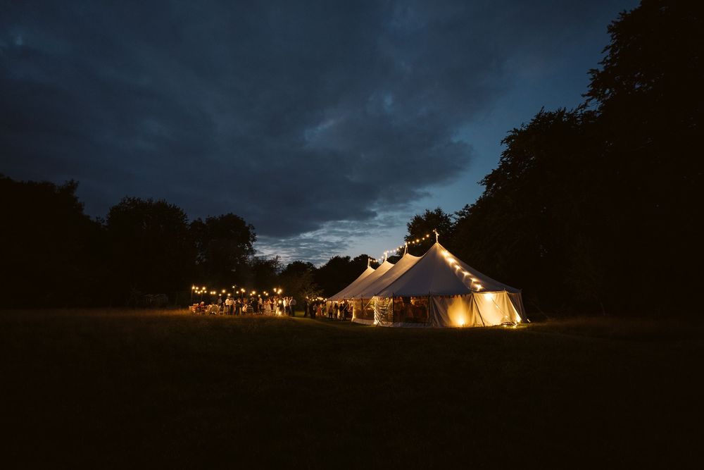 Beautiful wedding marquee lit up at night under a dramatic cloudy sky in Surrey