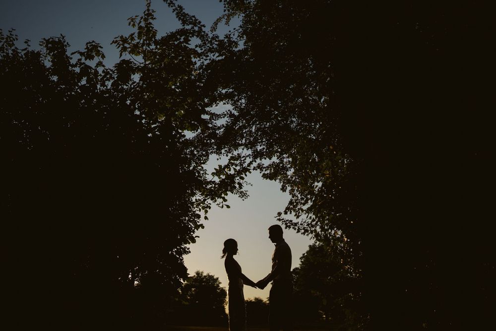 Silhouette of bride and groom at sunset framed by trees, Surrey wedding photography