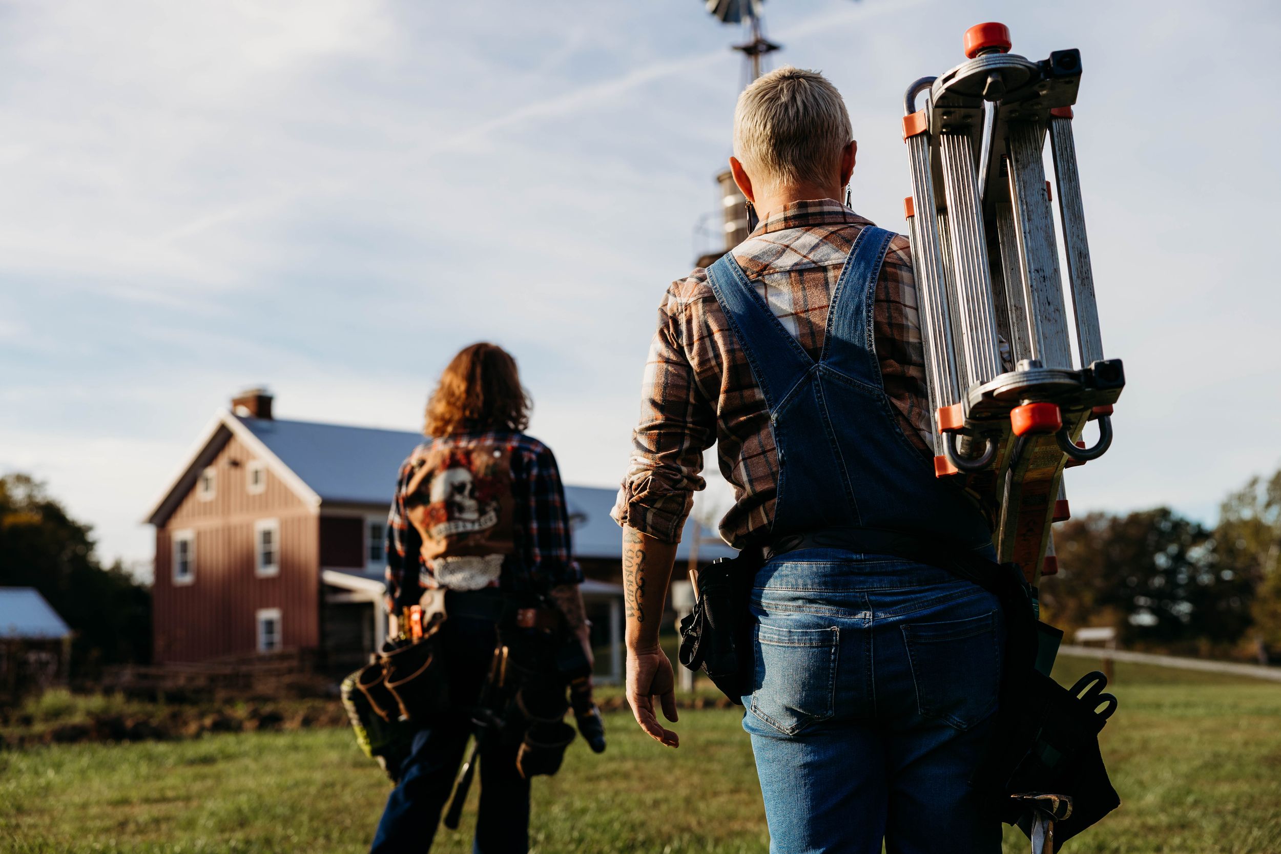 Photographer in denim capturing outdoor photos in a grassy field during golden hour.