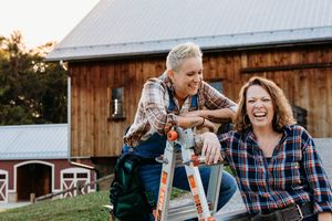 Couple shares joyful moments during outdoor engagement photoshoot at rustic barn setting during golden hour.