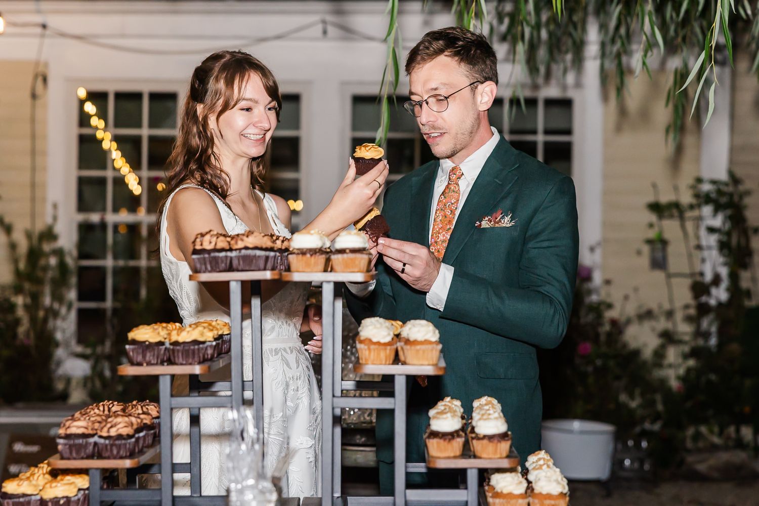 Two people serve desserts from a multi-tiered display stand at an elegant event.