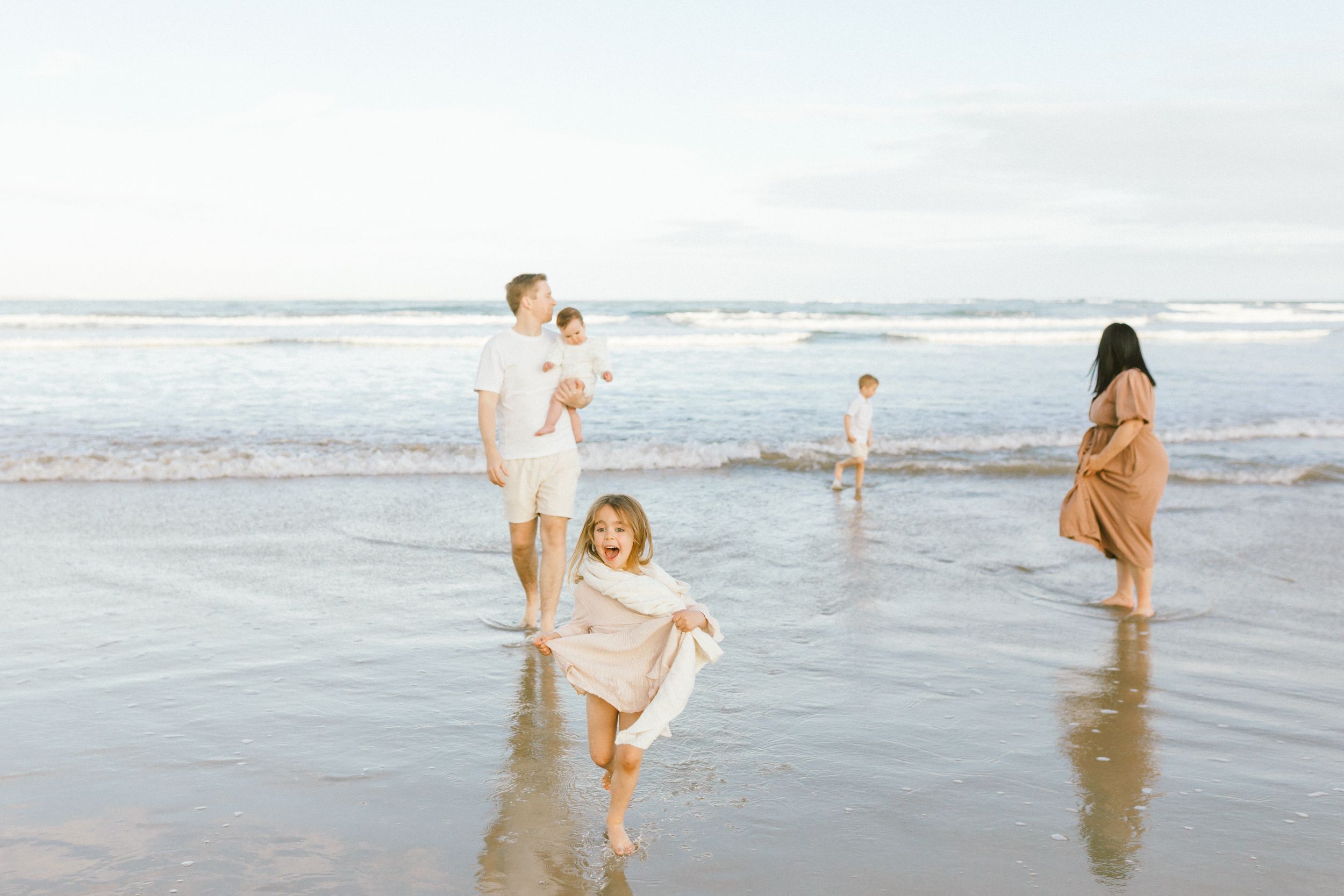 Carefree beachgoers frolicking in the shallow ocean waters on a bright summer afternoon.