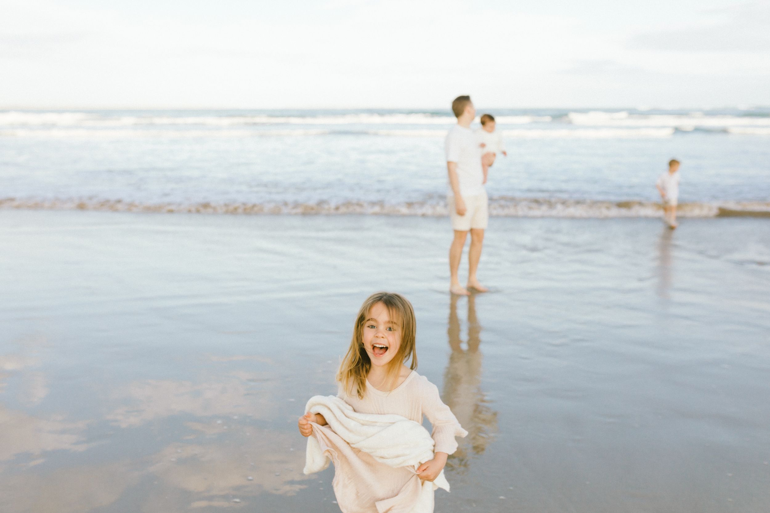 People enjoying a sunny day playing and splashing in the gentle waves at a serene beach.