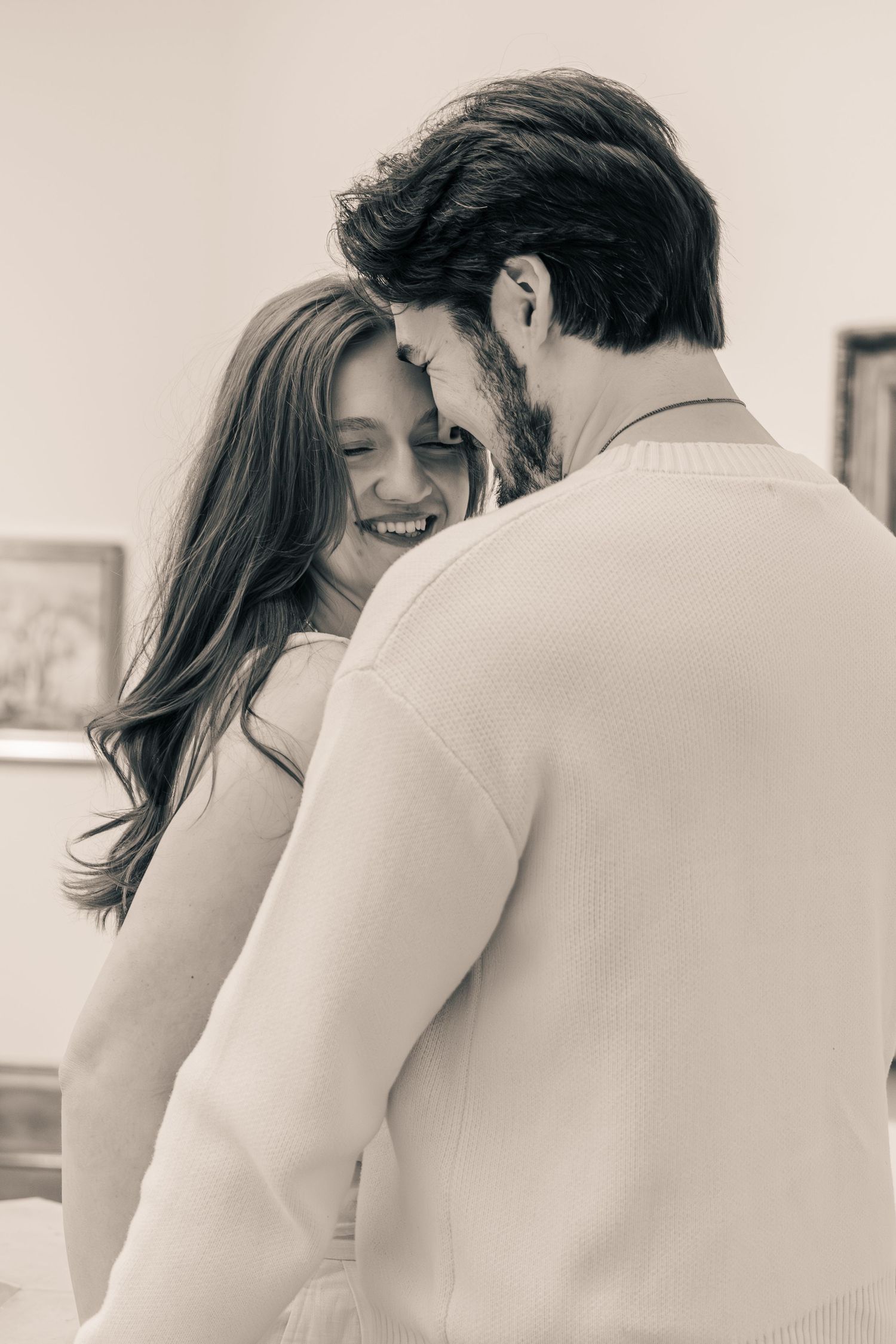 Romantic black and white photo of a smiling couple embracing intimately indoors.