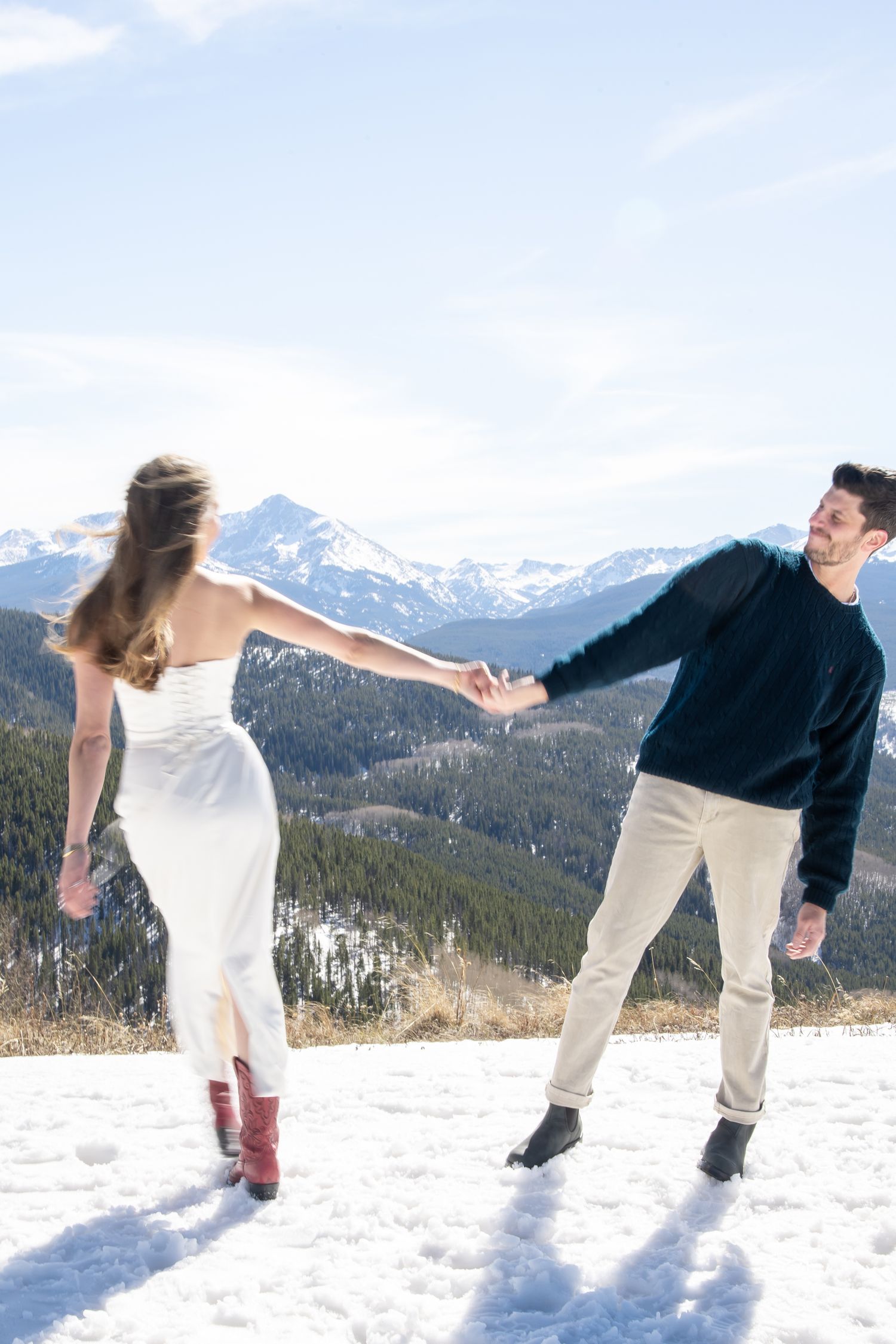 Fashionable couple spins around during cute winter engagement photo session in Vail Colorado.