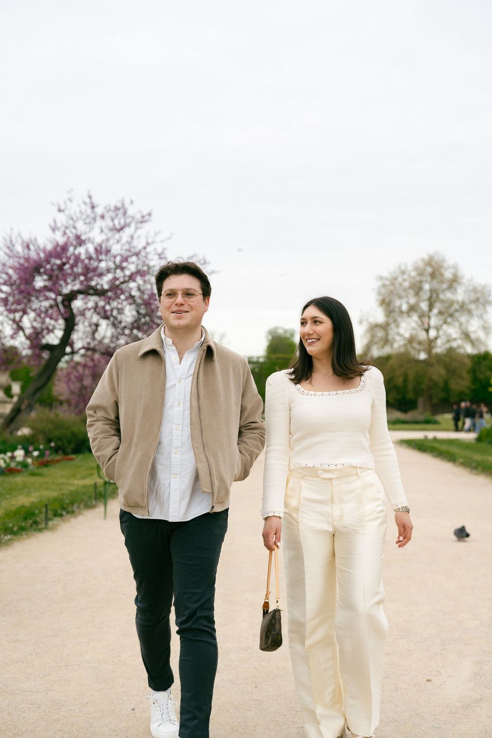 Paris couples cinematic editorial photography session Tuileries spring cherry blossom season, Paris engagement outfits garden inspiration
