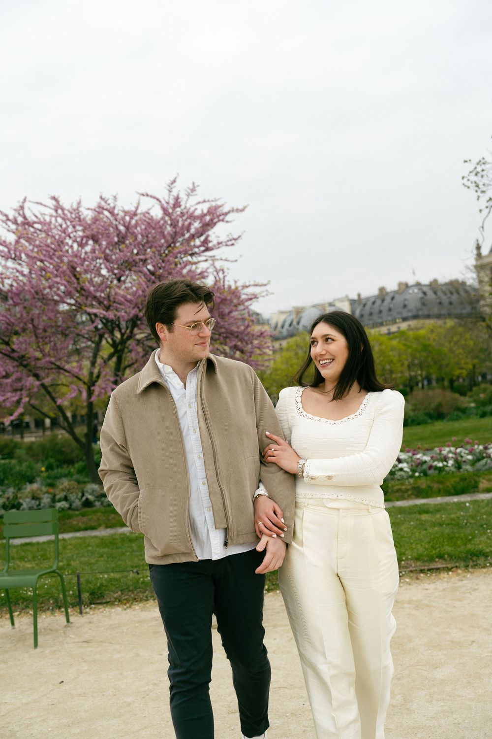 Couple walking together in a Parisian garden with cherry blossom trees, paris film photographer, paris editorial photographer