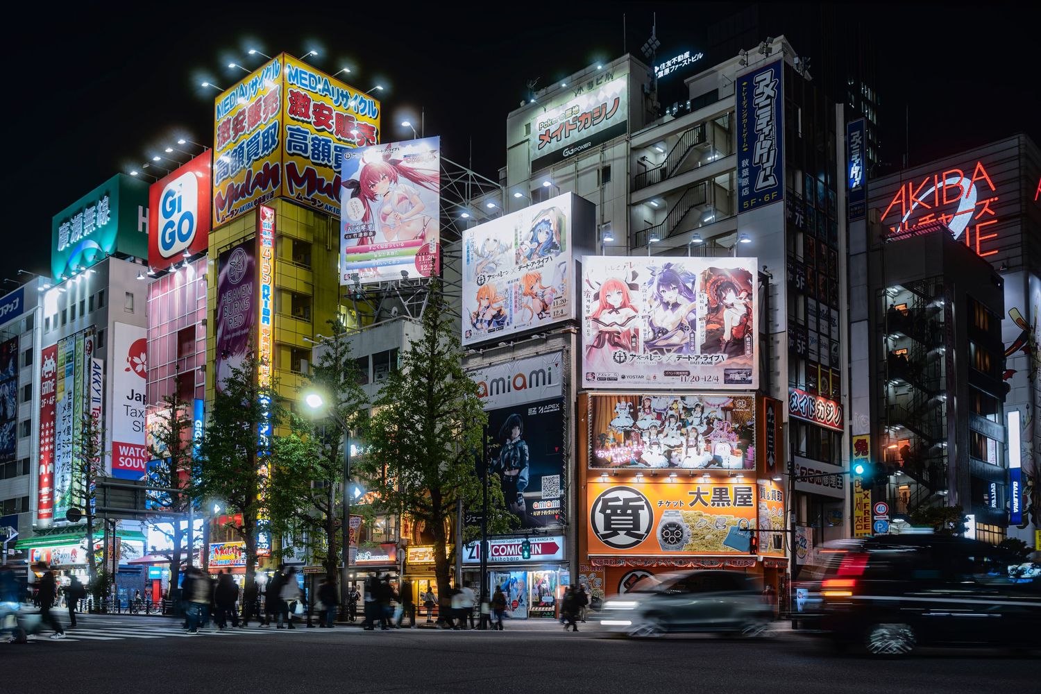 Vibrant neon-lit streets of Akihabara, Tokyo at night with colorful billboards and busy urban intersection.