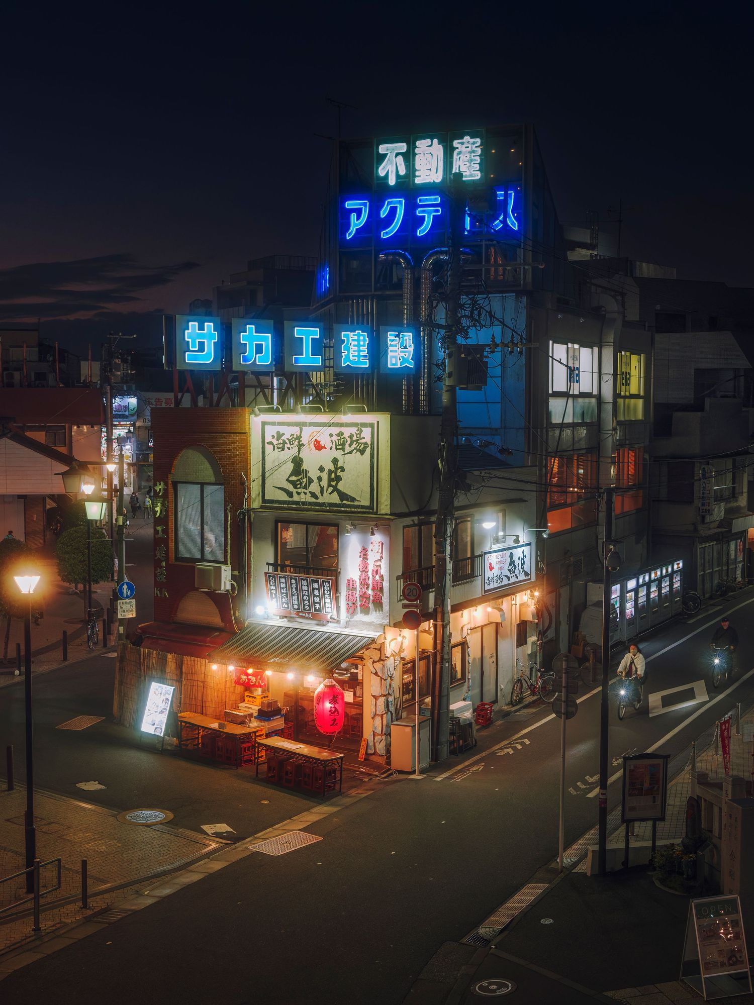 Neon-lit Japanese street corner at night with glowing kanji signs illuminating a multi-story building in an urban cityscape.