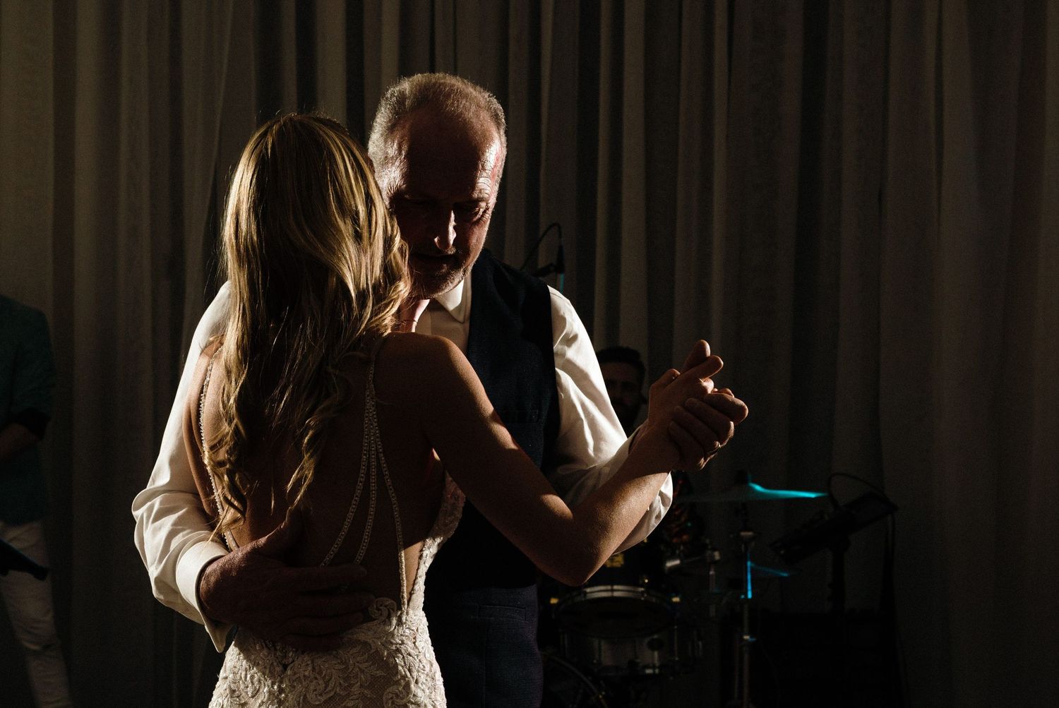 Silhouetted couple dancing intimately in dark room with dramatic backlighting creating romantic atmosphere.