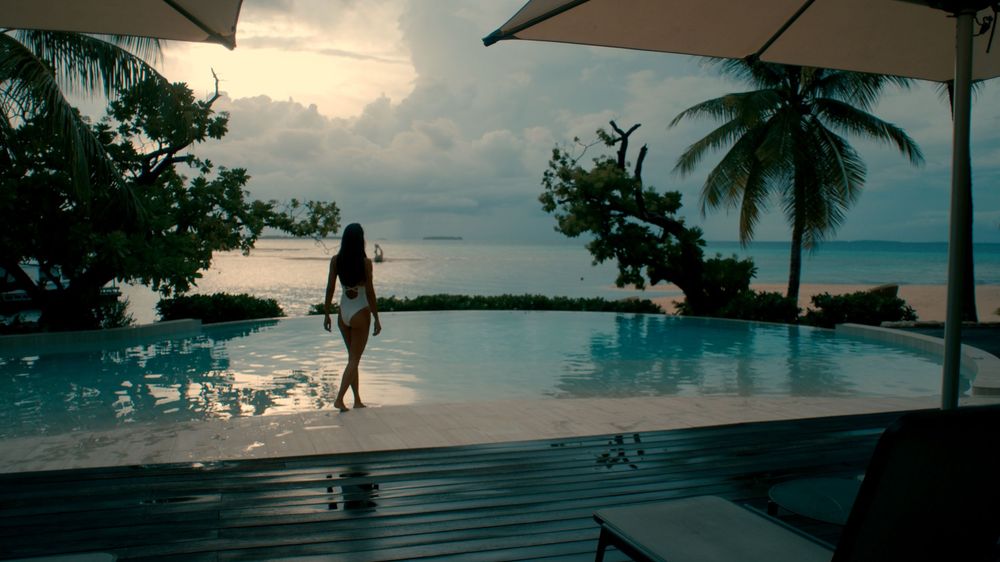 A panoramic view of a beachfront resort with palm trees and lounge chairs at sunset.