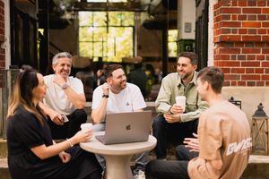 Group meeting in progress at brick-walled office space with natural lighting.