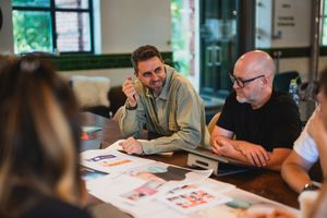 Team members having a business discussion around a conference table in modern office setting.
