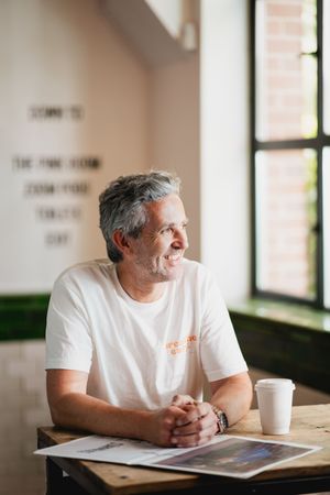 Person wearing white t-shirt sitting at desk near windows in modern office setting.