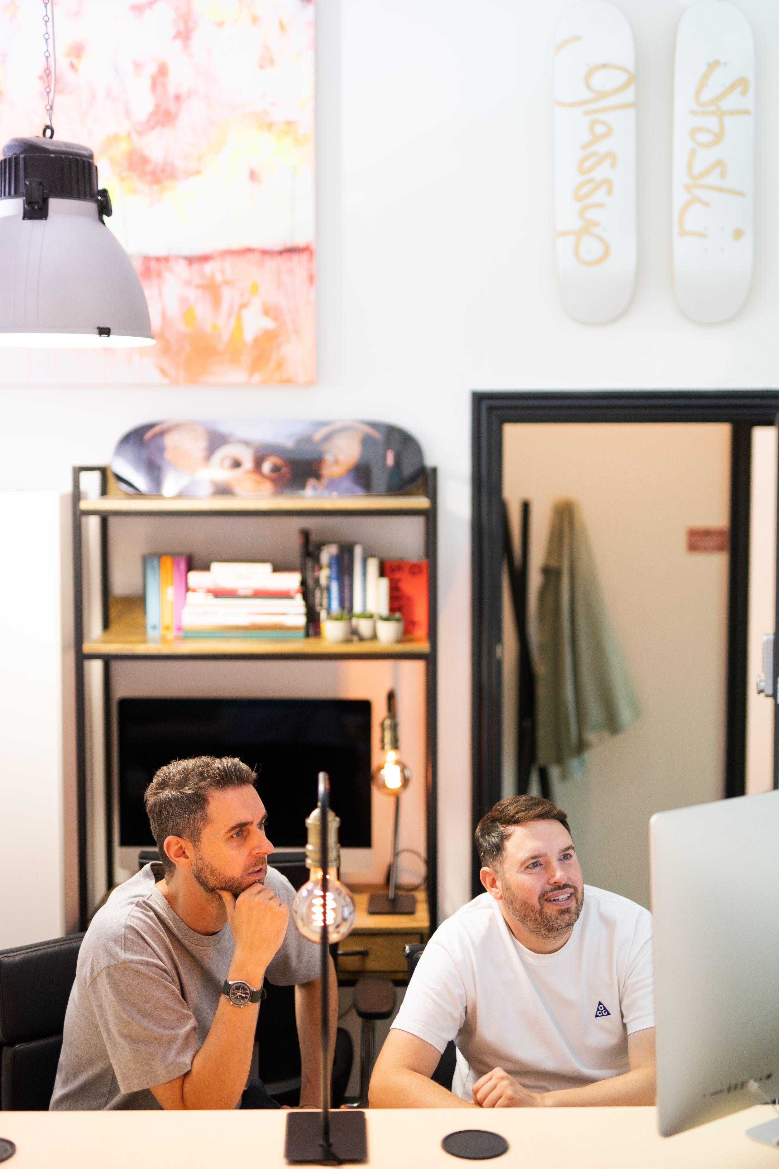 Two colleagues collaborating at a desk with computers in a modern office space.