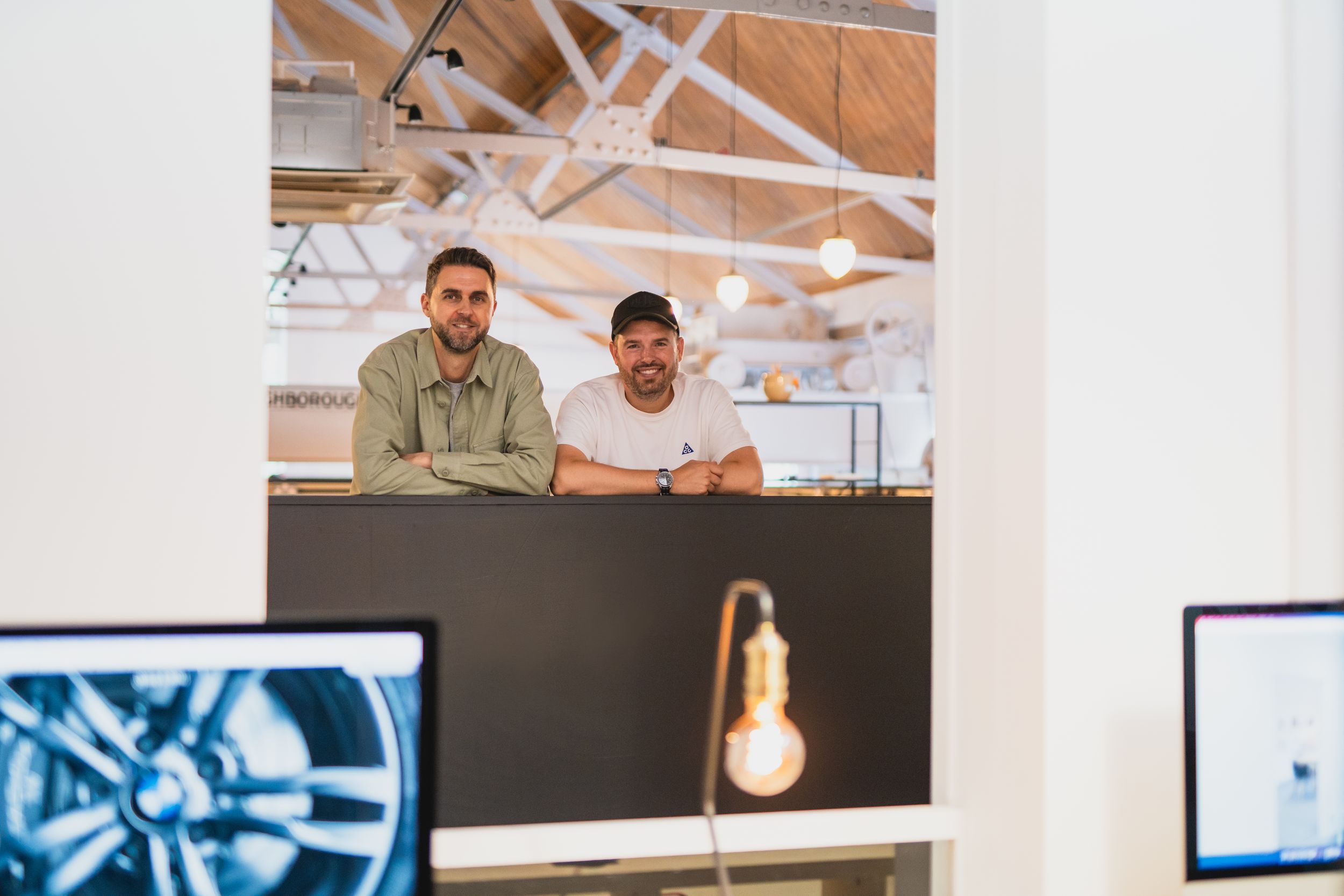 Two people working at a desk in a modern office space with exposed brick walls and natural lighting.