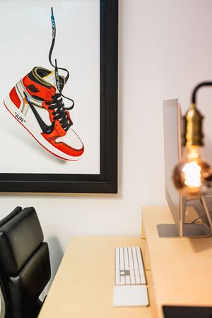 Red and white Nike Air Jordan sneaker artwork displayed in black frames on a white wall above a desk.