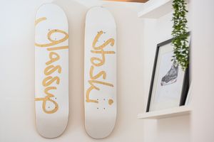 White decorative skateboards mounted on wall with gold lettering as office decor.