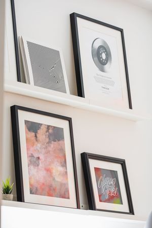 Gallery wall displaying framed artwork and prints in minimalist style on white wall.