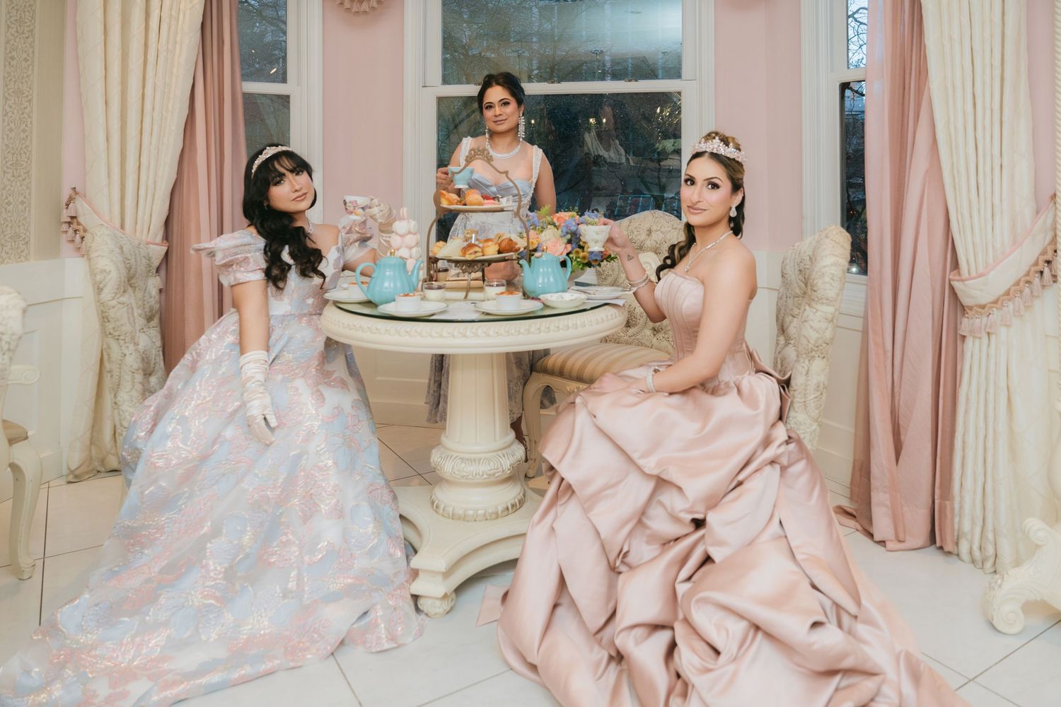 A collection of elegant pink wedding dresses with voluminous tulle skirts and ornate details displayed in a bridal boutique.