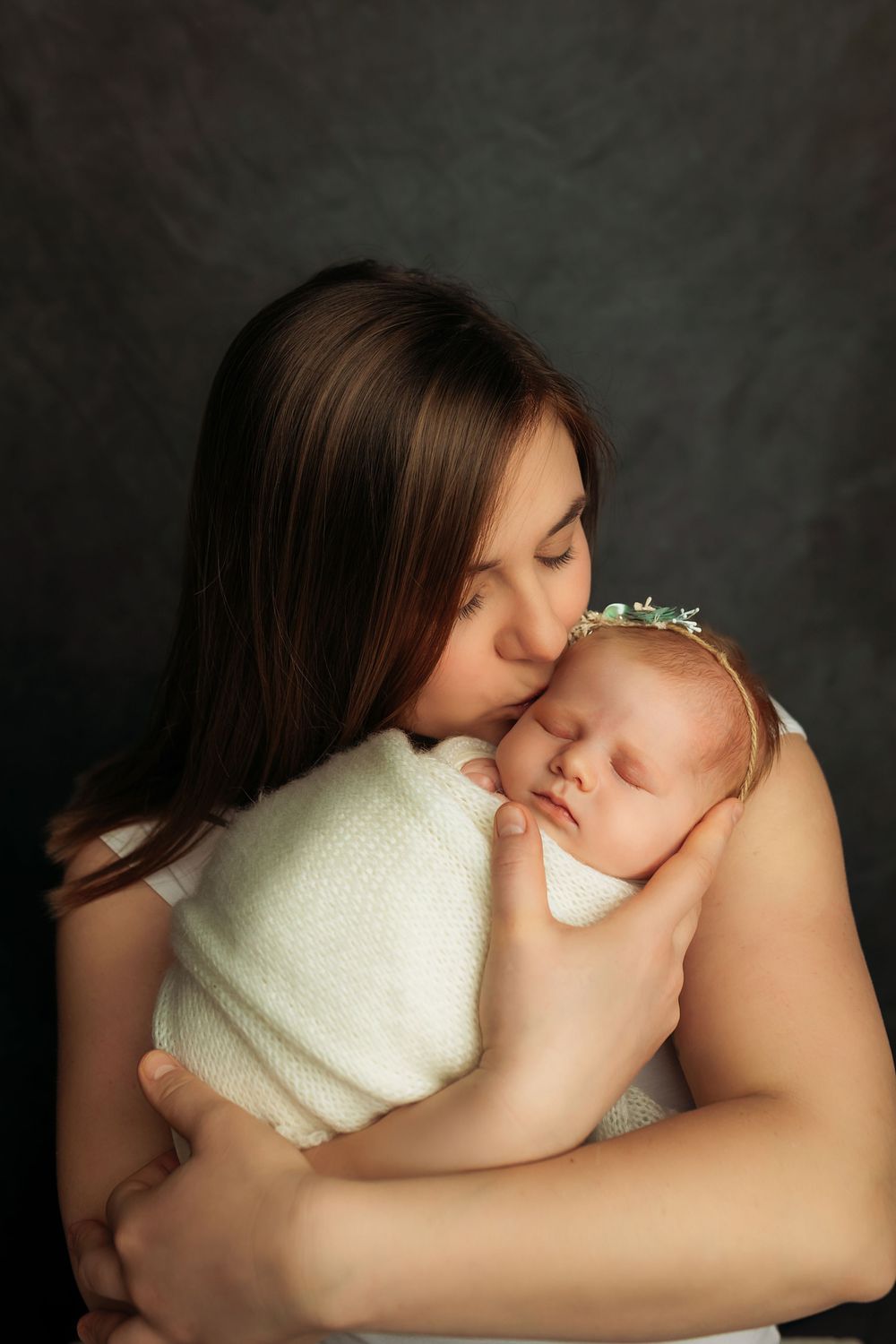 A series of intimate black and white portraits showing tender moments between parent and newborn against dark background.
