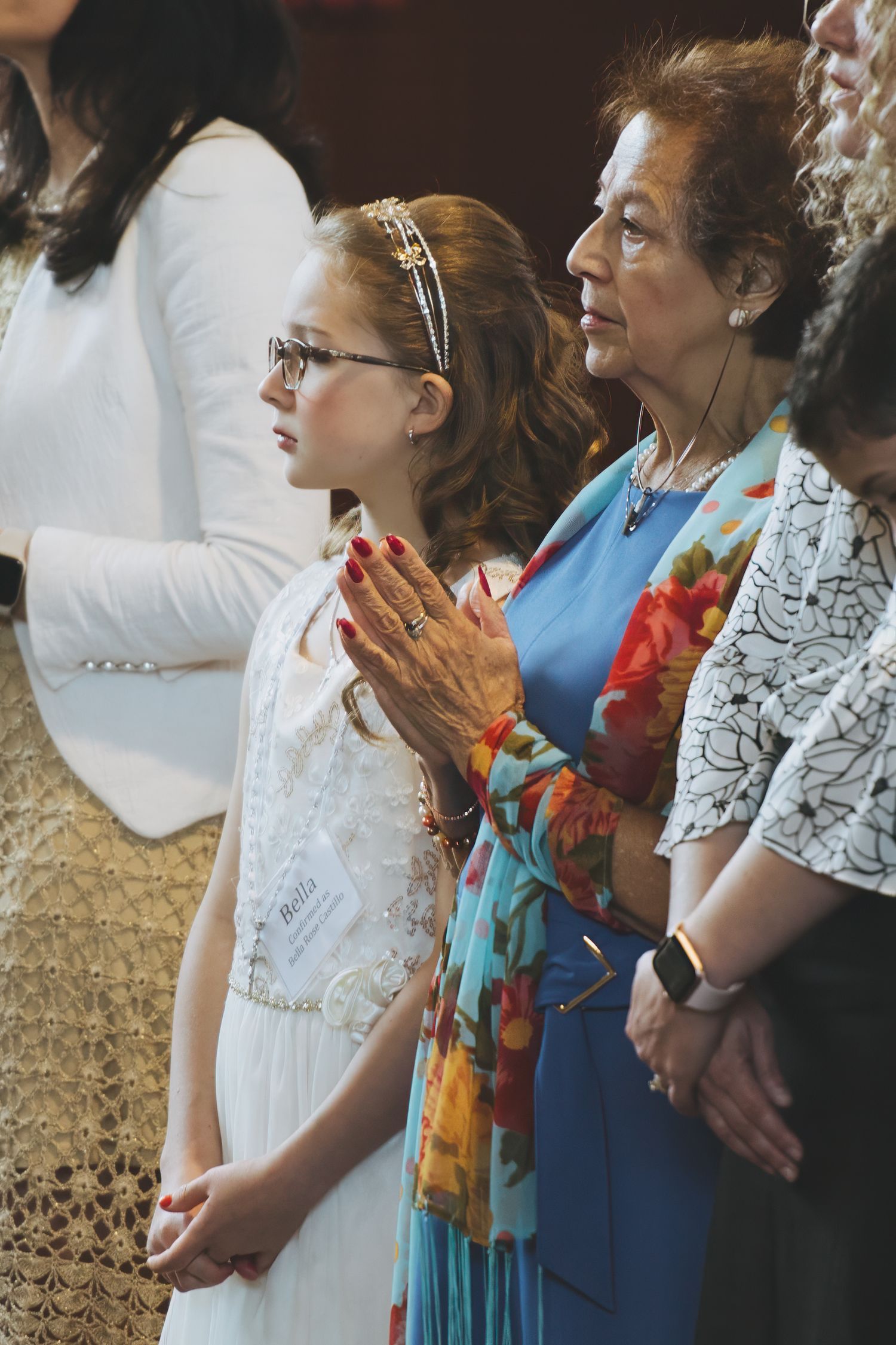 A group of women stand together wearing white lace and blue dresses at a formal event.