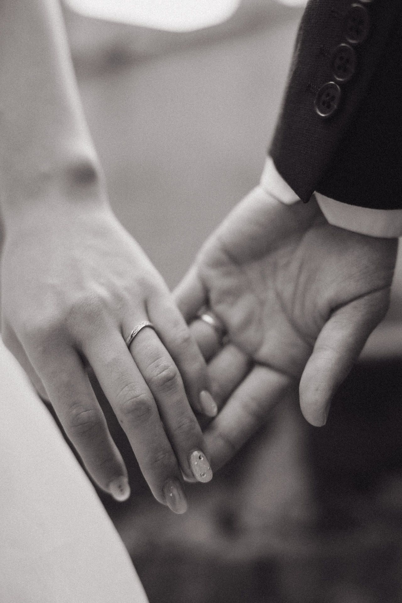 Two hands gently intertwined in a black and white photograph showing a tender moment of connection.