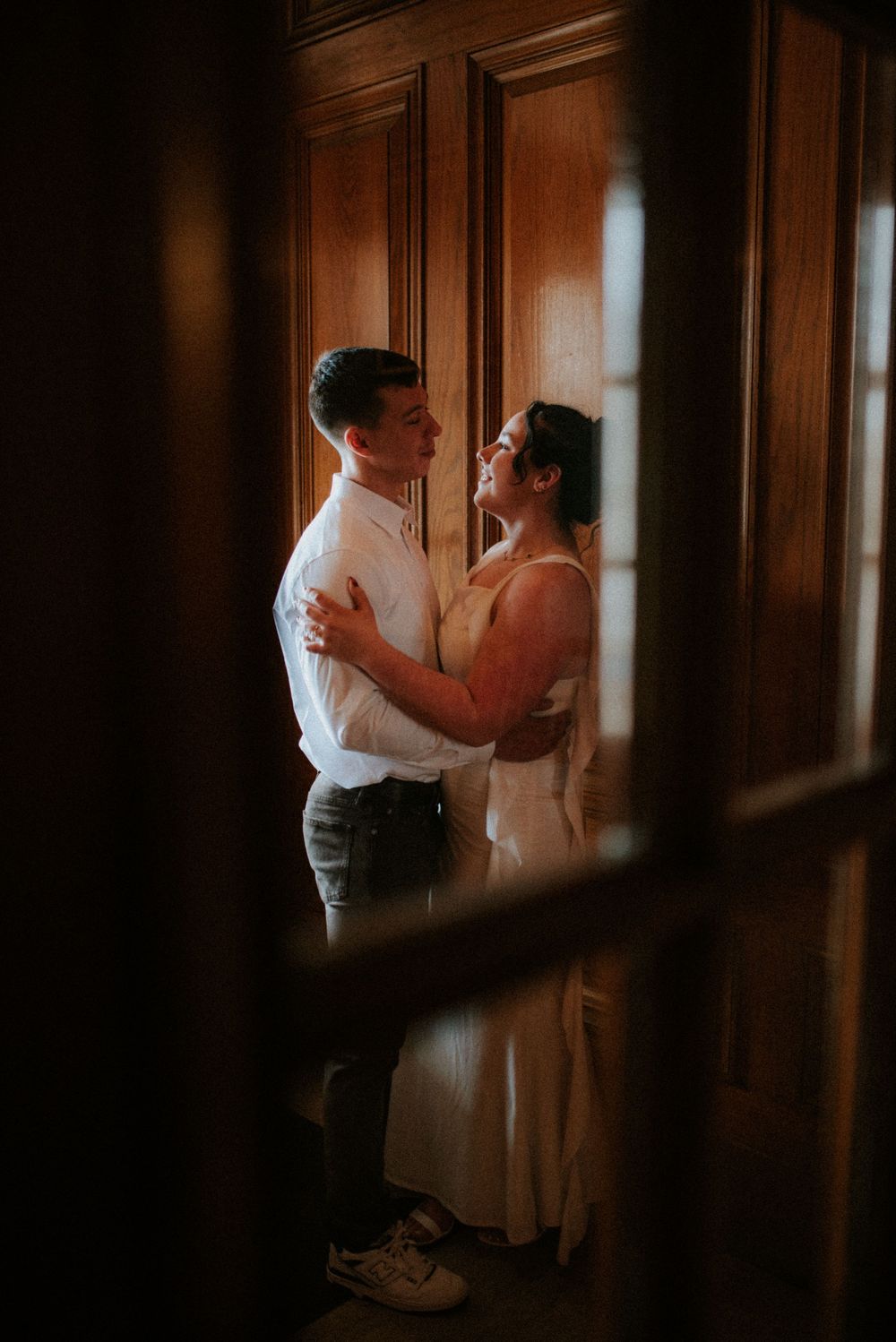 Engagement session of a couple framed within a window looking out.