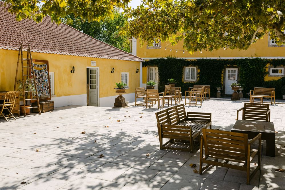 Courtyard at Quinta Nova do Hespanhol in Lisbon with yellow walls, trees and relaxed seating area for wedding guests