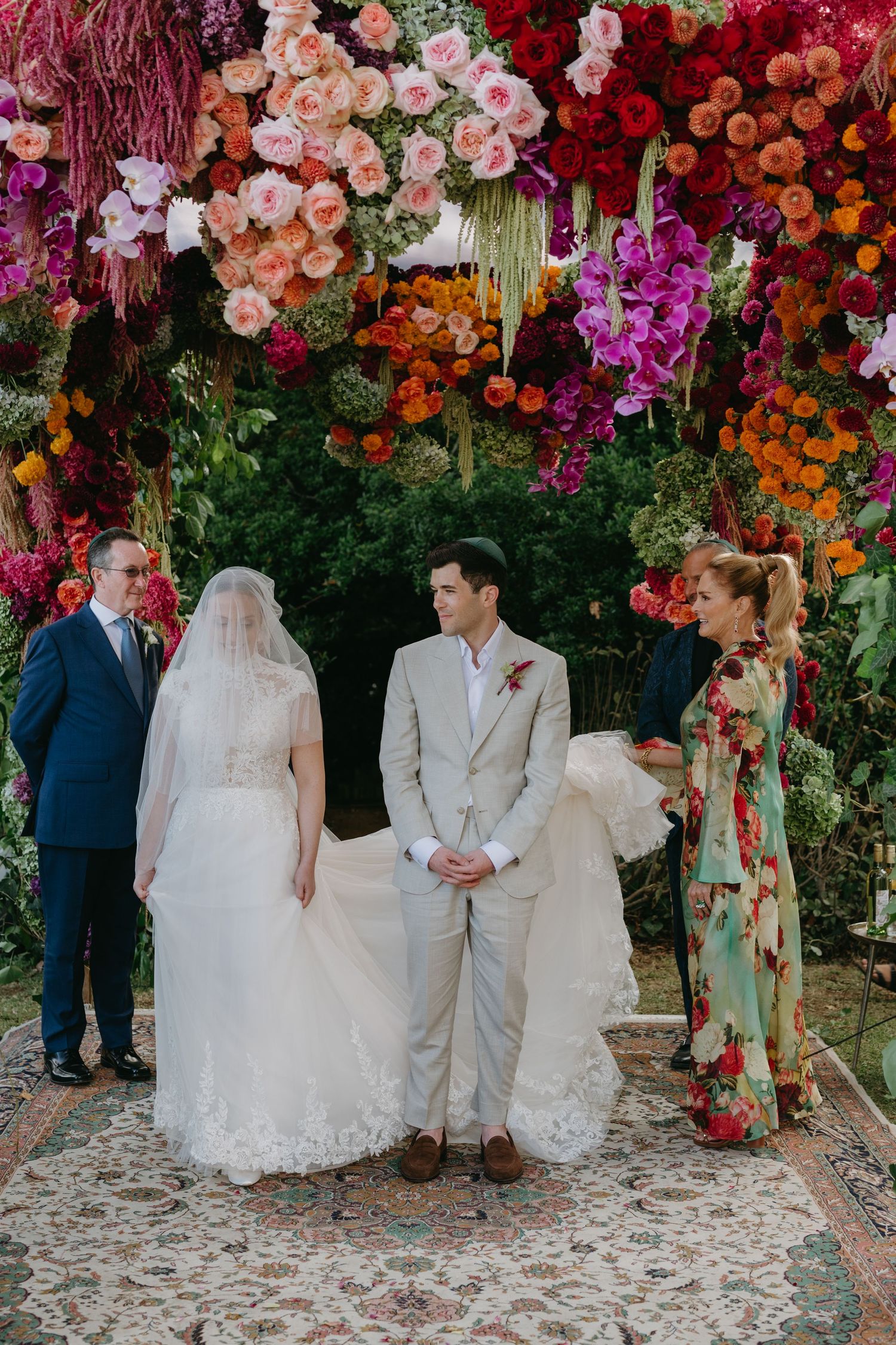 A wedding ceremony setup with a spectacular wall of colorful flowers and greenery as the backdrop.