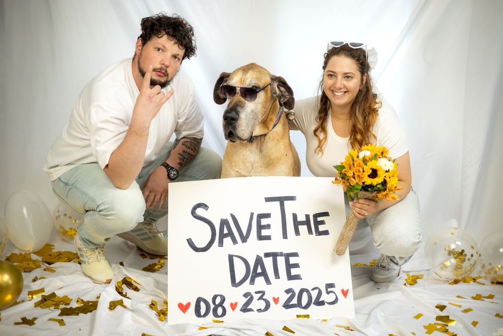 A playful engagement photo session with a couple and their golden retriever surrounded by autumn leaves and save the date text.