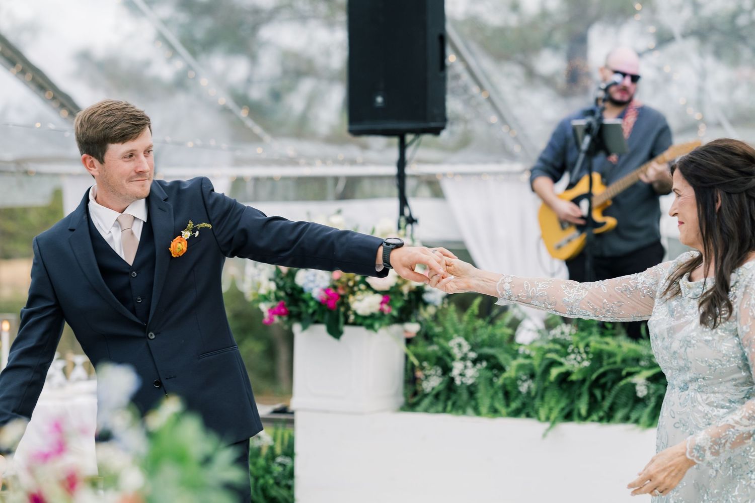 Groom and Mother of Groom dancing in front of live band under tented reception at a Spring wildflower wedding.
