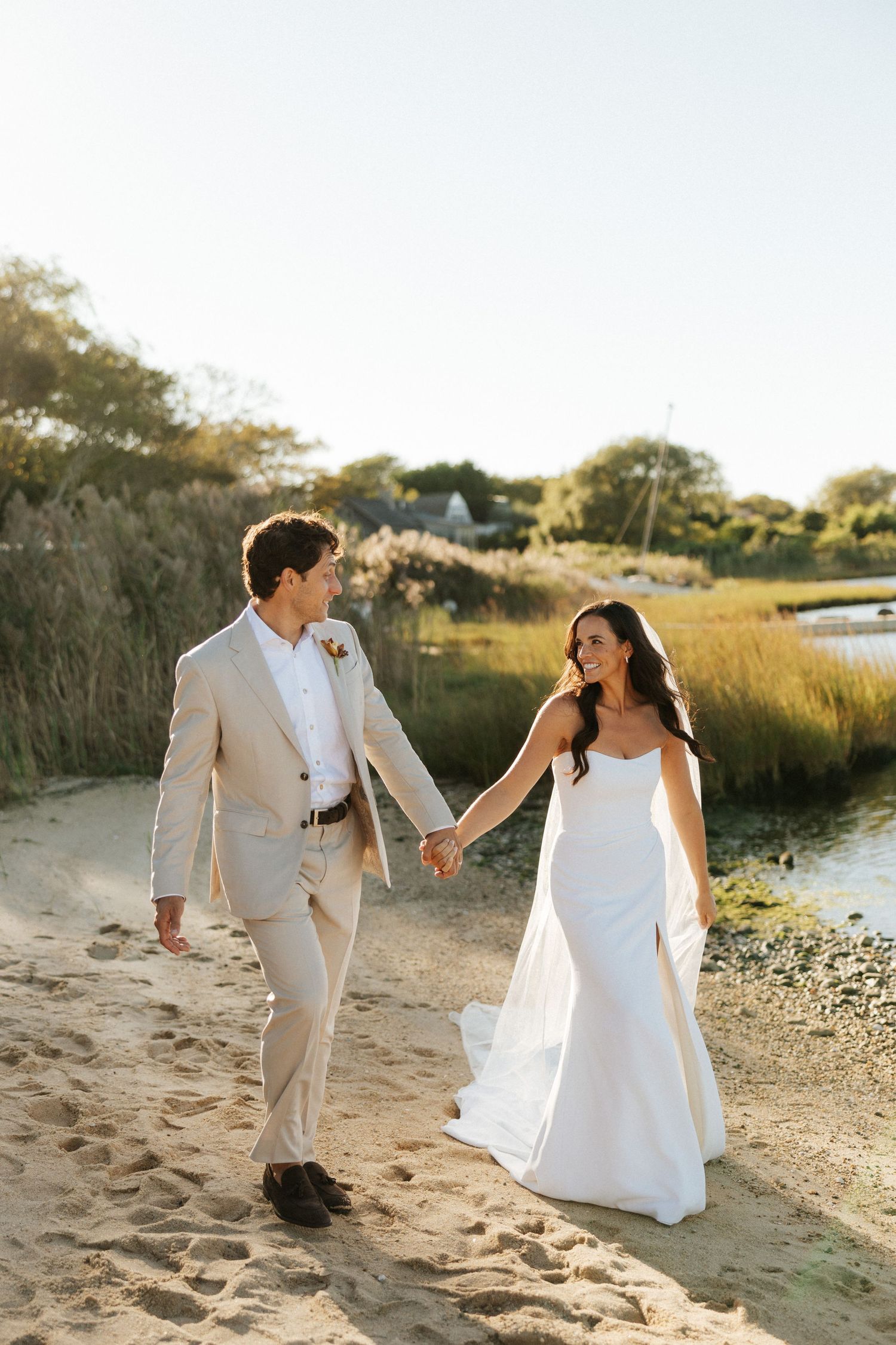 Bride and groom hold hands on Long Island beach