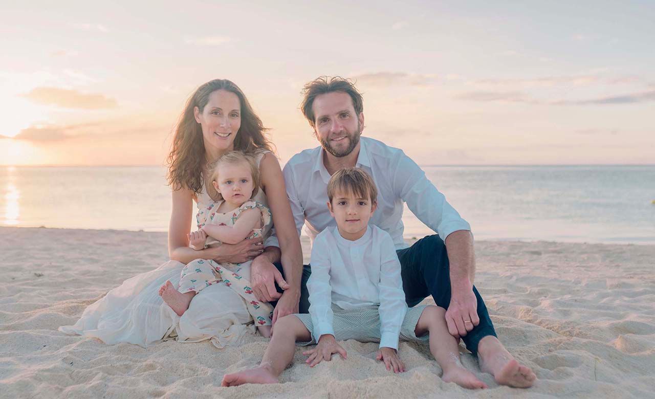 Family portrait on sandy beach during golden hour.