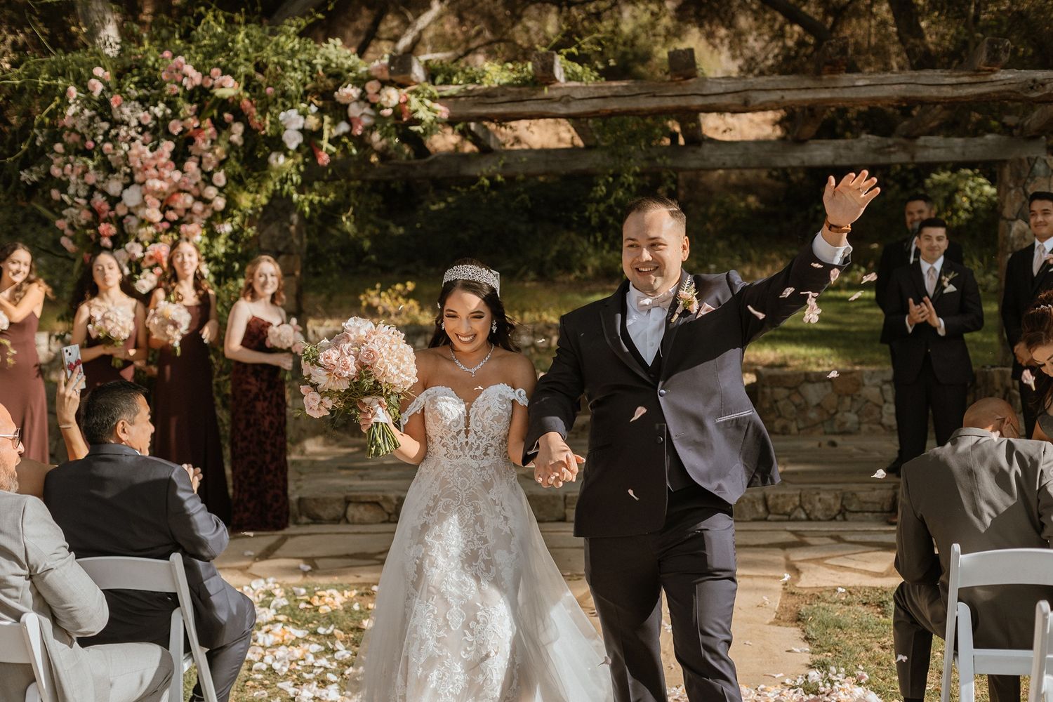 Bride and groom walk down the aisle after wedding ceremony outdoors, surrounded by guests and floral decorations at The Havens Country Club.