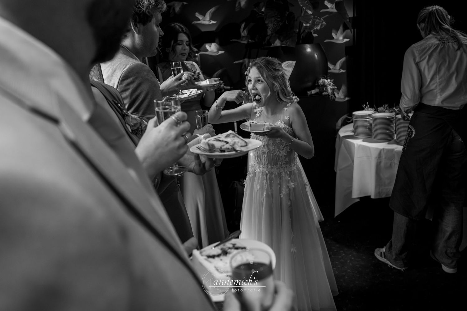 Wedding guests gather around a dessert table filled with sweet treats and pastries at an elegant reception.