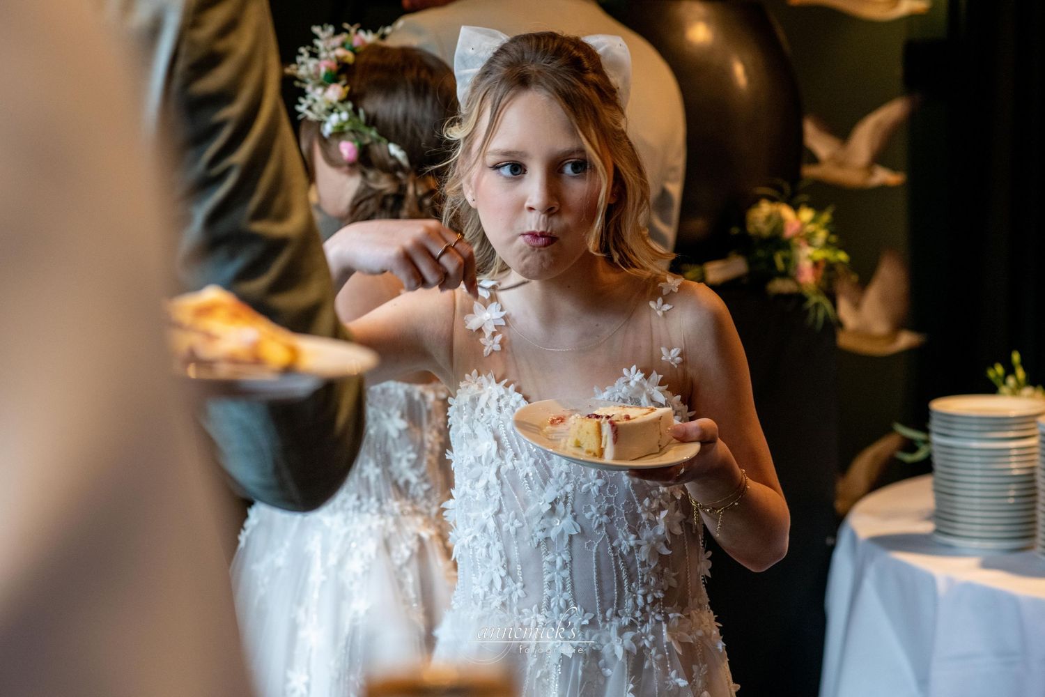 Guests holding delicate teacups at an elegant wedding reception with warm ambient lighting.