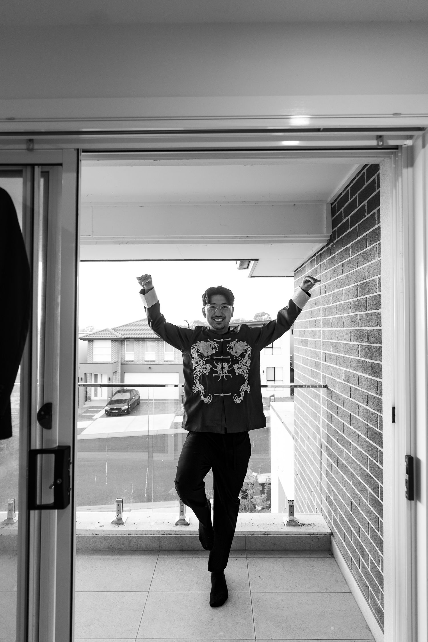 A sequence of black and white photos shows a person jumping and posing playfully in a corridor with white walls.