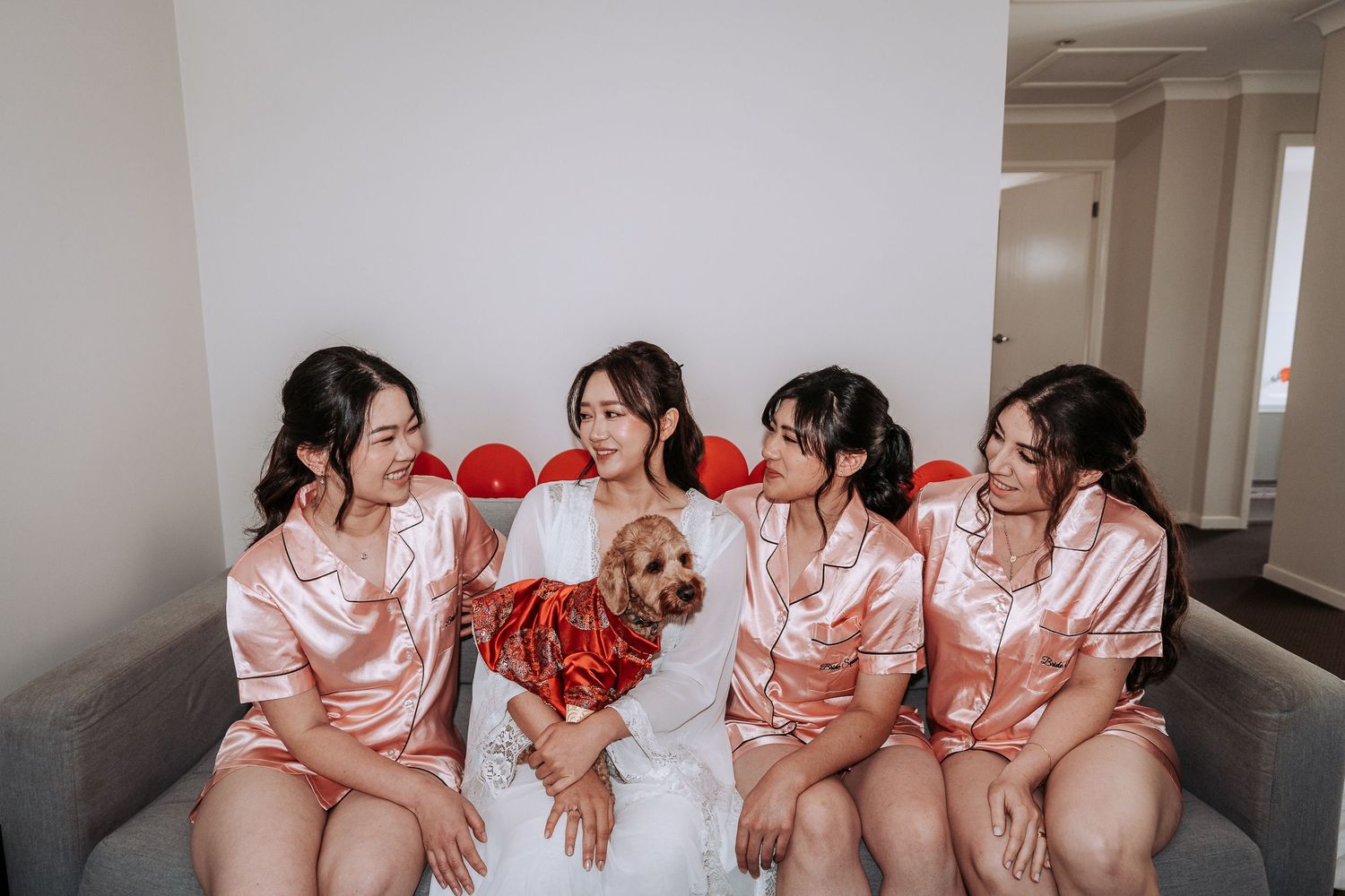 Group wearing matching pink robes sitting together during wedding preparations.