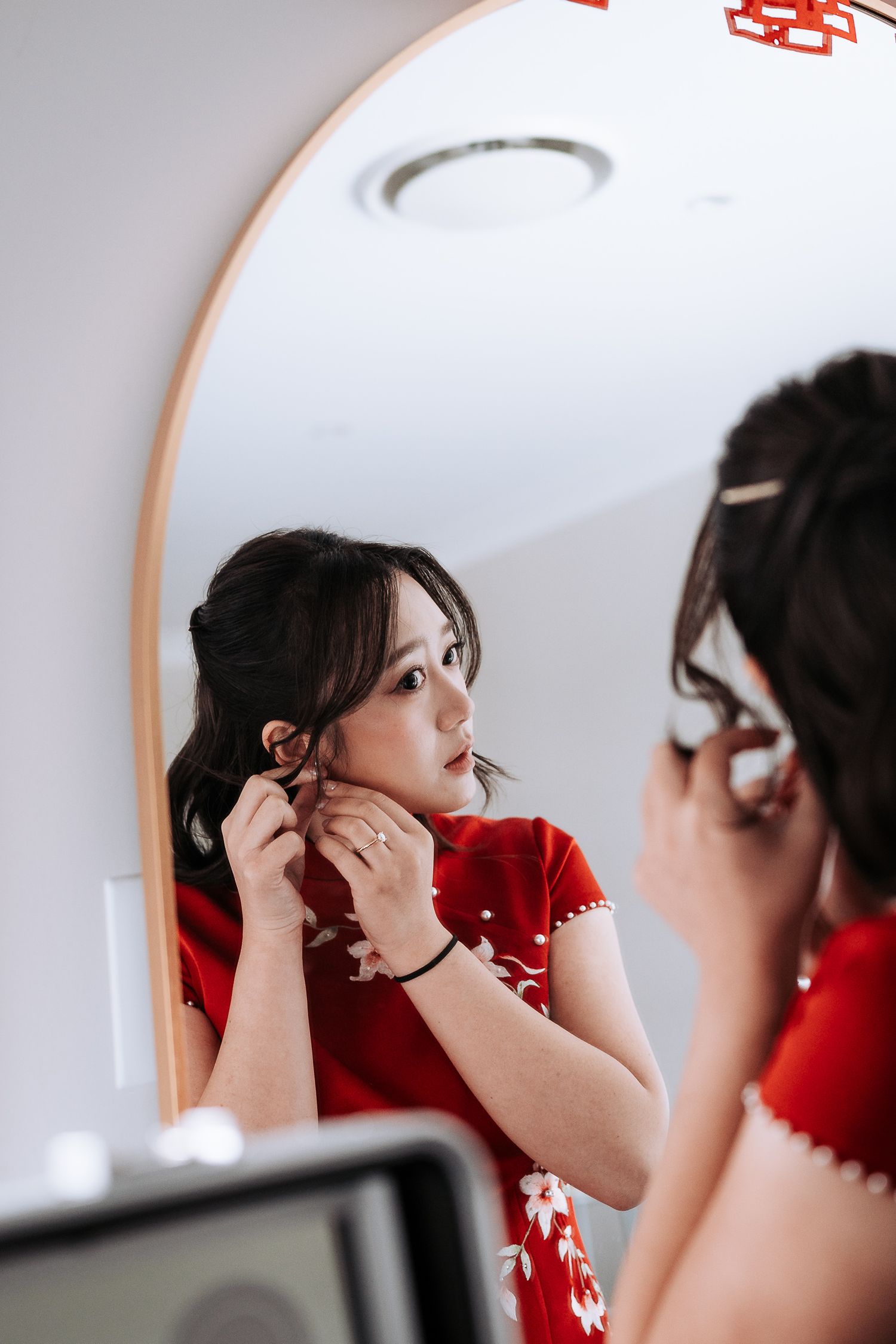 Close-up sequence of someone adjusting their hair in a mirror while wearing a red outfit.