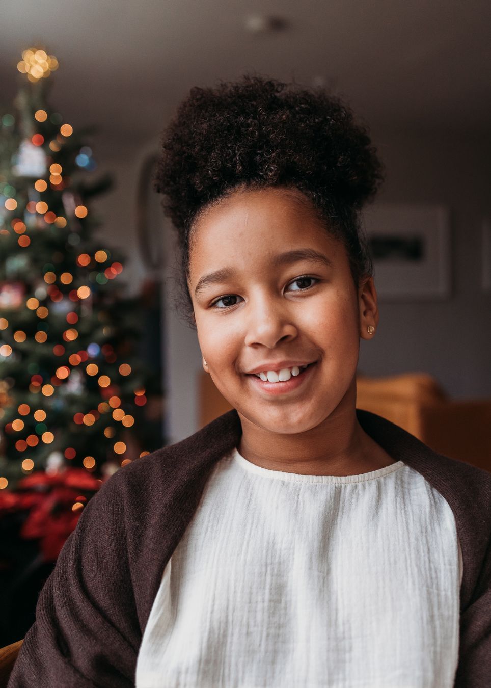 A small child in a navy sweater covers their nose with their hand in a sequence of playful expressions.