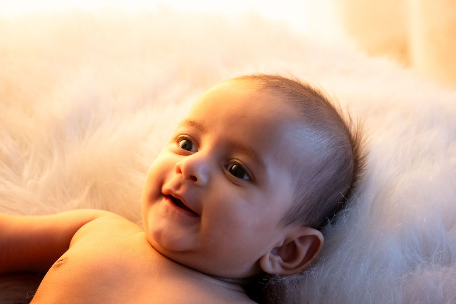 A baby looks up with a curious expression in a series of four similar photos taken in warm lighting.