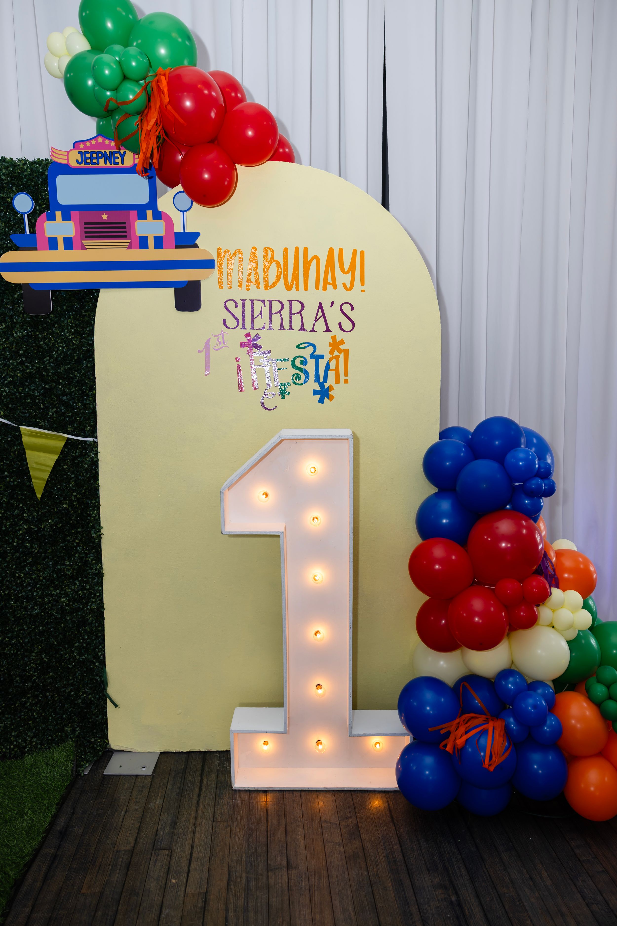 Mabuhay Sierra's 1st Fiesta birthday backdrop with illuminated number one marquee sign and colorful balloon decorations.