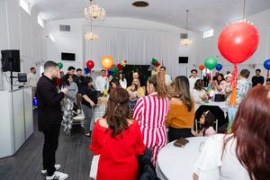 Colorful balloon-decorated party venue with guests socializing at tables during a festive indoor celebration.